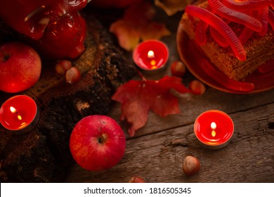 Halloween Food Still Life Abstract Background With Pumpkins, Apples, Cake, Gummy Worms, Skull Red Drink And Candles