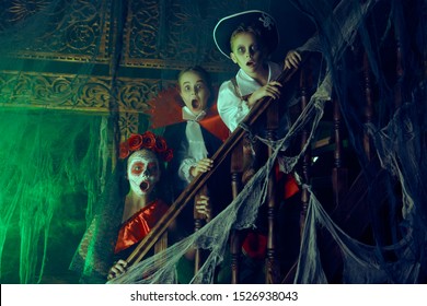 Halloween. Funny Scared Kids In Carnival Costumes Wander Through The Old Castle On Halloween.