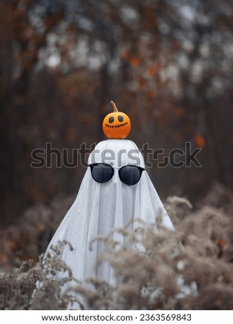 Halloween ghost costume with sunglasses. Cheerful pumpkin on the head. Ghost bed sheet