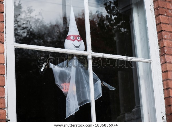 Halloween ghost puppet hanging in windows split\
into square quarters by\
muttins