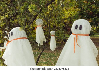 Halloween ghosts decoration hanging on tree branches. Easy autumn DIY outdoor yard decor and holiday ideas for party. Selective focus, copy space - Shutterstock ID 2208076835