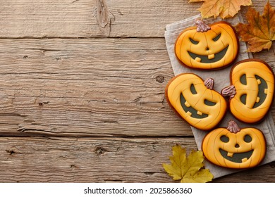 Halloween gingerbread cookies and autumn leaves on wooden planks, copy space