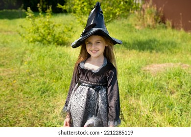 Halloween girl going to collect candy. Trick-or-treating. Guising. Jack-o-lantern. Child in carnival costume witch outdoors. Celebrate halloween. Girl in forest smiling and holding basket of sweets. - Shutterstock ID 2212285119