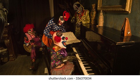 Halloween. A group of clowns having fun around the piano. Clown playing the piano.