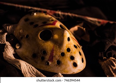 The Halloween Hockey mask of dead. Put on the table in the dark horror environment, with bandage and old rusty blade. Close up