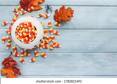 Halloween Holiday Candy Corn In A Generic Ghost Bowl And Decorations Over A Blue Wooden Background With Free Space For Text For Trick Or Treat. Top View.