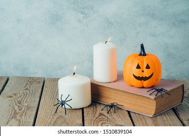 Halloween Holiday Concept With  Jack O Lantern Glitter Pumpkin Decor, Old Book And Candles On Wooden Table