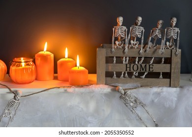 Décoration de maison d'Halloween. Squelettes de jouet en plastique dans une boîte en bois sur une cheminée contre un mur bleu foncé. Une guirlande de squelettes. Cobweb sur la commode. Bougies oranges et lanterne.