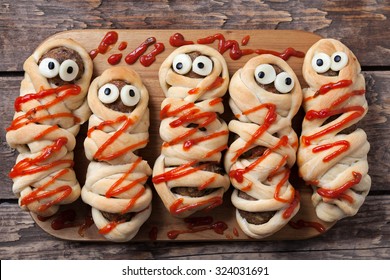 Halloween Homemade Food Sausage Meatball Mummies Wrapped In Dough, Baked And Covered With Fake Blood Sauce Decoration For Holiday Celebration Party On Vintage Wooden Background. Rustic Style And