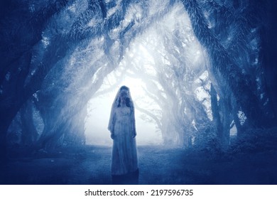 Halloween horror concept. Creepy female ghost wearing bloody bride gown while standing in the misty forest