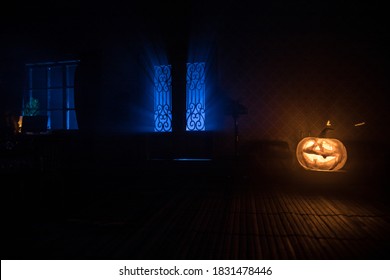 Halloween Horror Concept With Glowing Pumpkin. A Realistic Dollhouse Living Room With Furniture, Door And Window At Night. Scary Zombies Outside. Selective Focus.