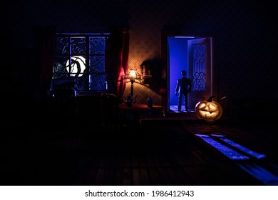 Halloween Horror Concept With Glowing Pumpkin. A Realistic Dollhouse Living Room With Furniture, Door And Window At Night. Scary Zombies Outside. Selective Focus.