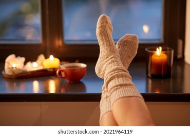 halloween, hygge and leisure concept - legs in socks on window sill at home in autumn