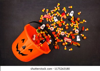 Halloween Jack o Lantern pail with spilling candy, above view on a dark background - Powered by Shutterstock