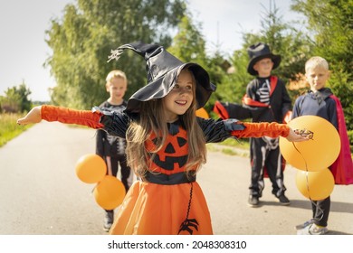 Halloween kids going to collect candy. Trick-or-treating. Guising. Jack-o-lantern. Children in carnival costumes outdoors. Witch and skeletons. Friends with orange balloons. celebrate halloween. - Shutterstock ID 2048308310