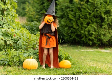 Halloween Kids. Portrait Happy Girl In Witch Costume, Black Hat On Scary Merry Holiday. Child With Pumpkin, Jack O Lantern, Basket Candy Sweet, Scaring Boo