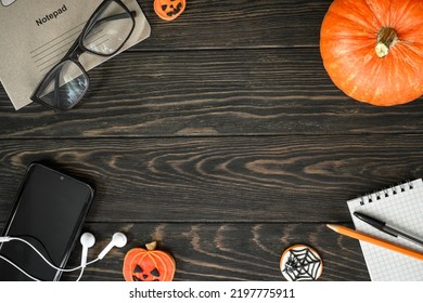 Halloween Lifestyle Background, Top View. Pumpkin, Sweets And Accessories On Dark Wooden Table, Flat Lay. Frame Of Hallowen Food, Glasses, Phone On Wood Planks With Space. Life And Halloween Concept.