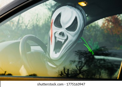 Halloween. A man in a terrible mask in a car in the driver's seat harvests pumpkins and scares