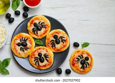 Halloween Mini Spider Pizzas Made From.pizza Crust,pizza Sauce,olive Oil,mozzarella Cheeses And Black Olives On Plate With White Wood Table Background.Art Food Idea Per Kids Halloween Party.Copy Space