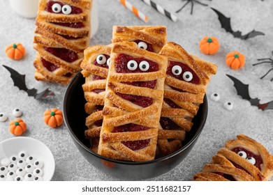 Halloween mummies pies with cherry filling and sugar eyes on a gray concrete background. Funny food idea. Holiday dessert. Top view - Powered by Shutterstock