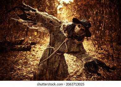 Halloween nightmare. An evil, insidious Scarecrow with a canvas bag on his head, in sackcloth clothes and a black hat, attacks in the dense autumn forest. Horror, thriller. - Shutterstock ID 2063713025