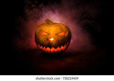 Halloween - old jack-o-lantern on black foggy background. Closeup of scary halloween pumpkins