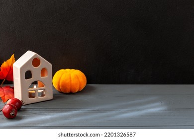 Halloween. On A Black And Gray Background Stands A House With A Fire Inside. Next To It Lie A Pumpkin And Small Apples