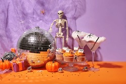 Composition à La Fête D'Halloween Avec Cupcakes, Disco Ball, Boissons Et Décorations Sur Table Orange Sur Fond Violet