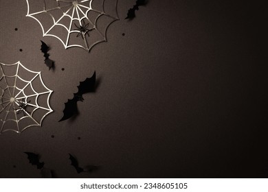 Halloween party decorations at night from bats, spider web and confetti top view. Happy halloween minimal holiday greeting card on dark background flat lay.