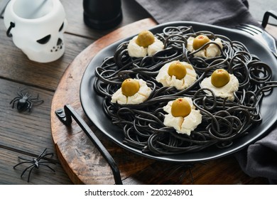 Halloween Party Italian Black Pasta Decorated Horror  Olives Like Eyes On Black Plate On Old Dark Table Background. Monster Face From Pasta. Halloween Decorations And Halloween Food Concept. Mock Up.