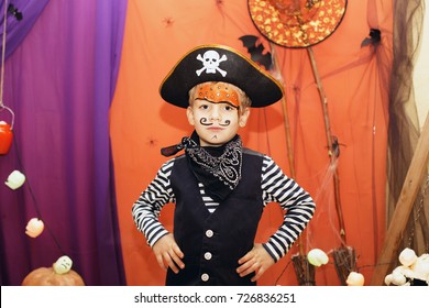 Halloween Party. A Little Boy In A Pirate Costume And A Makeup On His Face Is Having A Good Time At The Halloween Party. Face Painting Kids. Child Among Halloween Decorations