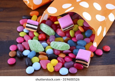 Halloween Party Trick Of Treat Candy With Candy Flowing From Orange Polka Dot Party Favor Bag On Dark Wood Background. 