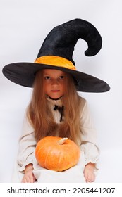 Halloween Portrait Of A Little Girl In A Witch Magic Hat. Little Child With Pumpkins. White Background. 