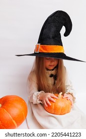 Halloween Portrait Of A Little Girl In A Witch Magic Hat. Little Child With Pumpkins. White Background. 