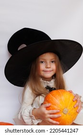 Halloween Portrait Of A Little Girl In A Witch Magic Hat. Little Child With Pumpkins. White Background. 