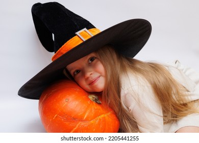 Halloween Portrait Of A Little Girl In A Witch Magic Hat. Little Child With Pumpkins. White Background. 