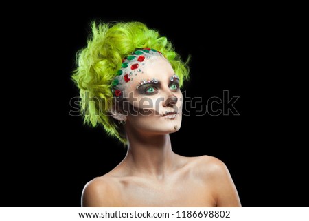Halloween. Portrait of young beautiful girl with make-up skeleton on her face. And green hair. Isolated on black background.