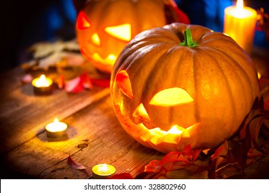 Halloween pumpkin head jack lantern with burning candles over wooden background. Halloween holidays art design, celebration. Carved Halloween Pumpkins with burning candles