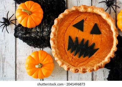 Halloween Pumpkin Pie With Jack O Lantern Face. Above View Table Scene On A White Wood Background.