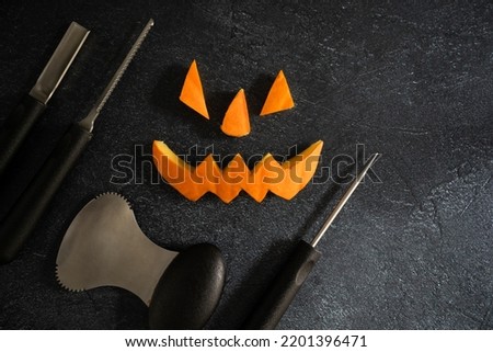 Halloween pumpkin pieces. Spooky laughing, scary carved Jack Lantern eyes, nose, mouth. Jack-o'-lantern elements with carving tools - spoon, saw blade, pointed and grove carver.