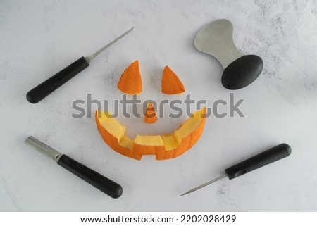 Halloween pumpkin pieces. Spooky laughing, scary carved Jack Lantern eyes, nose, mouth. Jack-o'-lantern elements with carving tools - spoon, saw blade, pointed and grove carver.