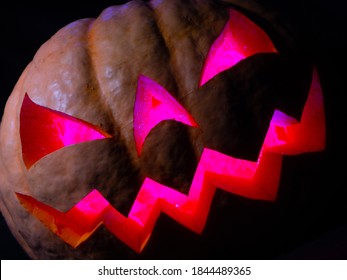 Halloween Pumpkin With Red Eyes, Scary Face And Spider On The Eye, Illuminated From Inside With Multicolored Lights, Very Scary Pumpkin For Halloween