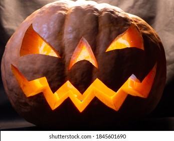 Halloween Pumpkin With Red Eyes, Scary Face And Spider On The Eye, Illuminated From Inside With Multicolored Lights, Very Scary Pumpkin For Halloween