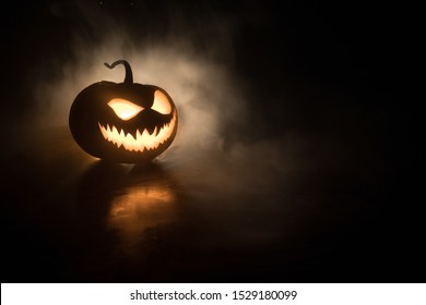 Halloween pumpkin smile and scary eyes for party night. Close up view of scary Halloween pumpkin with eyes glowing inside at black background. Selective focus - Shutterstock ID 1529180099