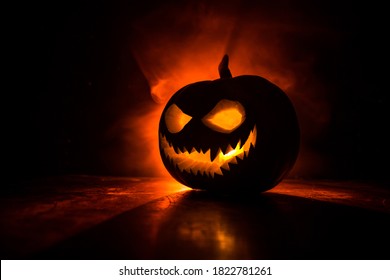 Halloween pumpkin smile and scary eyes for party night. Close up view of scary Halloween pumpkin with eyes glowing inside at black background. Selective focus - Shutterstock ID 1822781261