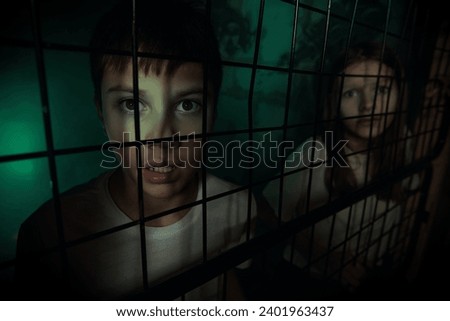 Halloween quest. Two teenagers - a boy and a girl - have fallen into the trap of a maniac and are looking in fear from behind the bars of the cage. Horror film for teenagers.