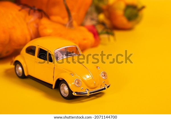 Halloween retro toy car on a yellow background\
with pumpkins in a spider web. Autumn mood for the holiday.\
29.10.2021 - Ukraine,\
Vinnytsia.