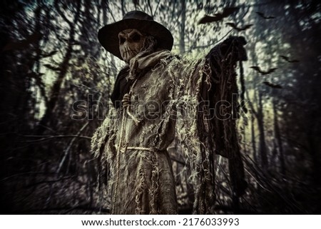 Halloween. A scene of horror, when an evil terrible Scarecrow with a bag on his head, in a sackcloth vestment and a black hat, stands in the thicket of the night forest. Horror, thriller.