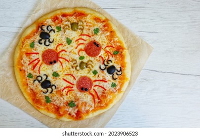 
Halloween spider pizza made from pizza dough,pizza sauce,mozzarella cheeses,black olives,green olives,salami and parleys on parchment paper with white wood background.Art food idea for kids party - Shutterstock ID 2023906523