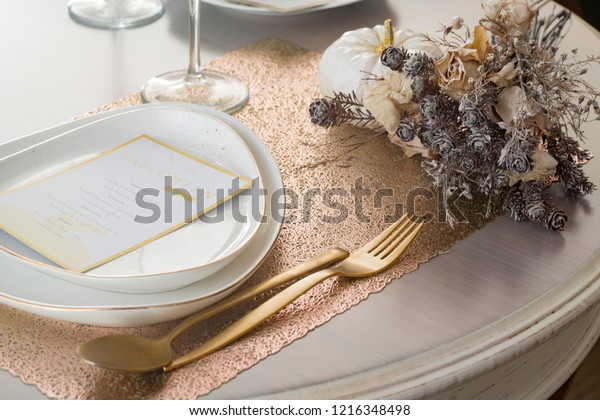 Halloween table setting with white pumpkins, menu card\
and gold cutlery. Luxury table setting. Thanksgiving decoration.\
Elegant holiday  table decoration with menu. Table setting with\
menu card. 